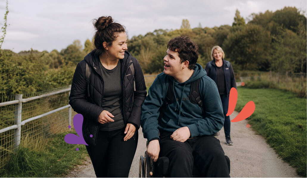 Young carer and boy with disability talking a walk