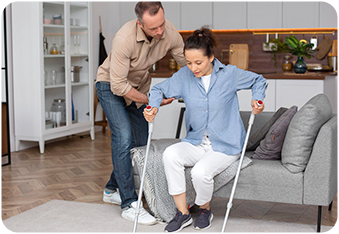 Woman with crutches getting help from a care worker with injury recovery